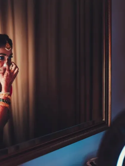 The bride applying her bindi in the mirror, a personal and significant moment of her bridal preparation.