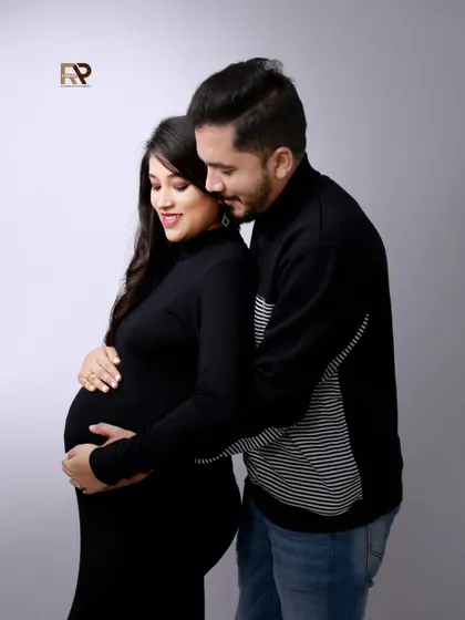 An intimate embrace. This couple, dressed in coordinating black outfits, shares a tender moment. The simple grey backdrop keeps the focus entirely on their connection.