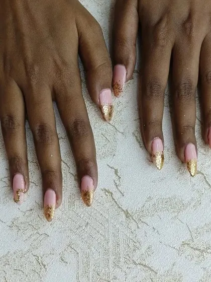 Glamour at your fingertips. This custom design on gel extensions combines a soft pink base with sparkling gold glitter tips and delicate stone accents for a truly luxurious and eye-catching look.