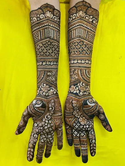 A gorgeous bridal design featuring heart-shaped peacock motifs on the palms. The arms are adorned with architectural patterns and delicate florals, creating a romantic and intricate look.