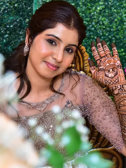 A happy bride showing off her intricate mehendi. The design is dense and detailed, perfect for a bridal look.