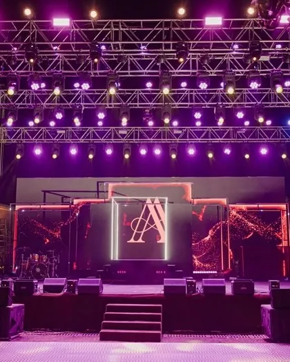 The concert-style stage setup for the Sangeet night. The powerful lighting rig and large LED screen with the couple's monogram ensured a high-energy, unforgettable party.