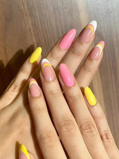 A bright and cheerful set with a mix of solid pink and yellow nails and abstract French tips.