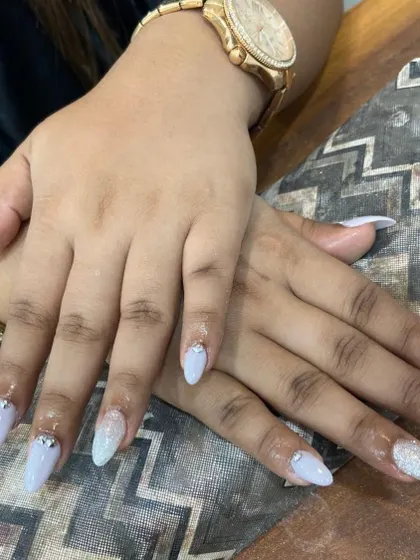Icy and elegant. These almond-shaped nail extensions are done in a cool, light blue shade with a subtle glitter accent nail and a few perfectly placed rhinestones at the cuticle for a clean, polished look.