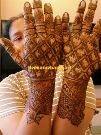 A happy client showing her full bridal mehandi. This design features a classic jaal (net) pattern that covers the entire hand and arm.