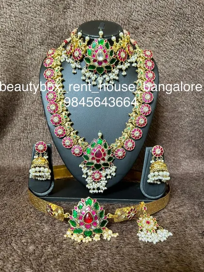 This kemp stone set features a beautiful combination of red and green stones with pearl drops. The rental includes a choker, haaram, and matching accessories.
