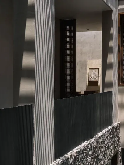 The upper-level corridor overlooks the courtyard, with sunlight filtering through the slatted roof. The design creates a sense of being in a modern, open-air pavilion.
