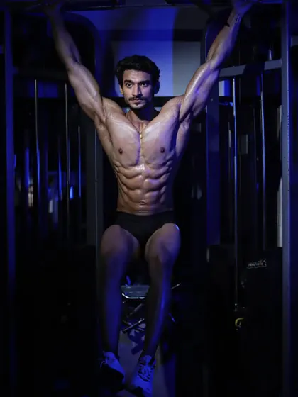 An abs and thigh pose, hanging from a pull-up bar. This demonstrates core strength and a lean, defined midsection.
