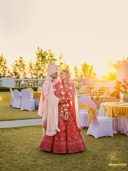The couple stands together in the golden hour light at their outdoor wedding venue, a perfect, romantic shot just after their ceremony.