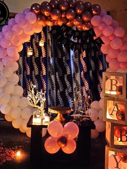 We created a romantic and intimate atmosphere for this celebration. The setup includes a beautiful balloon arch in pink, white, and rose gold, with a candlelit path of flower petals leading to the main display.