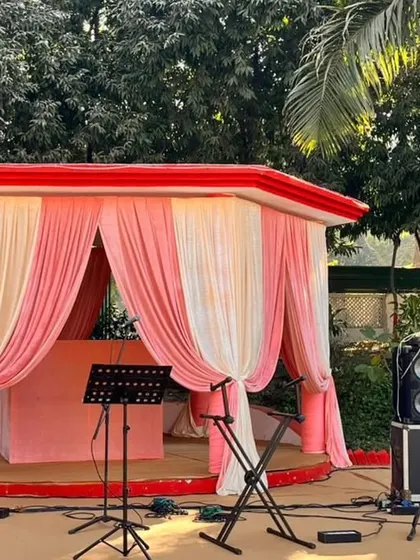 The stage for live music, elegantly draped in pink and cream fabrics, ready for a soulful performance to entertain the guests.