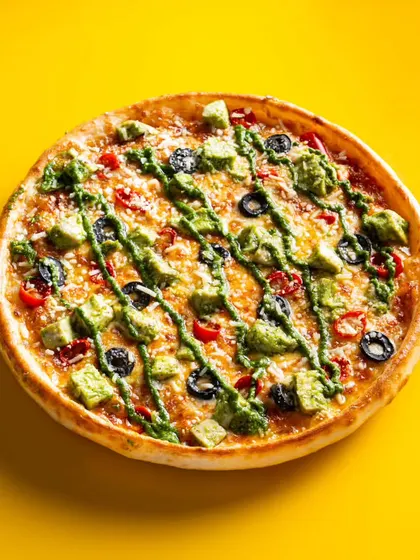 An avocado and olive pizza with a pesto drizzle. We ensure that even with multiple toppings, the image remains clean, vibrant, and focused on the dish.