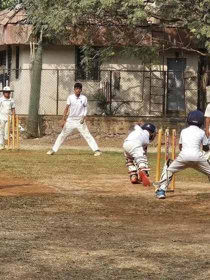 A classic scene from a practice match, with the batsman focused, the wicketkeeper alert, and fielders in position. These sessions are crucial for applying skills learned in the nets.