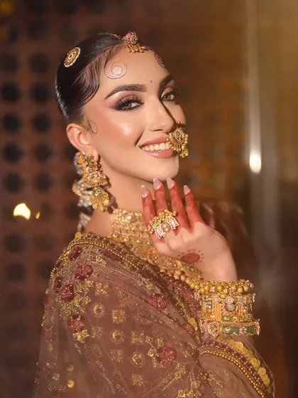 A joyful, candid shot that captures the bride's personality. The makeup is flawless, with a radiant glow that looks stunning in the warm light.