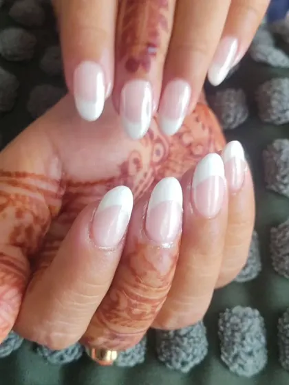 This is a classic French manicure with a slightly thicker white tip on oval-shaped nails. It's a beautiful look that works well for both daily wear and special events.