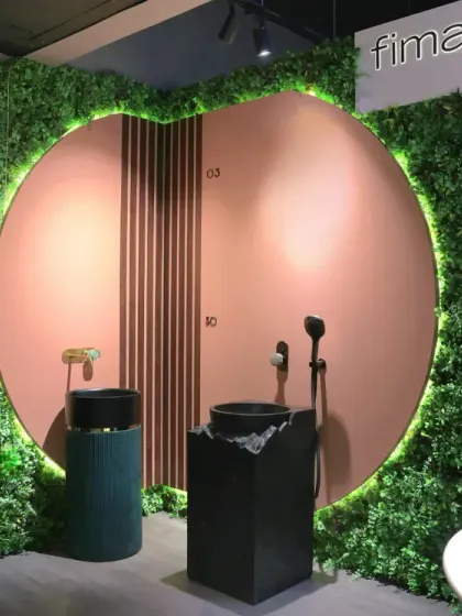 This display features a striking circular backdrop framed by a lush green wall with integrated lighting. It creates a biophilic, nature-inspired setting to showcase modern basins and shower fixtures, making the products pop.