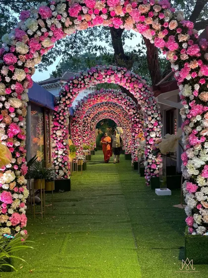 A magical entrance tunnel made of cascading floral arches in shades of pink and white, creating a spectacular welcome for guests.