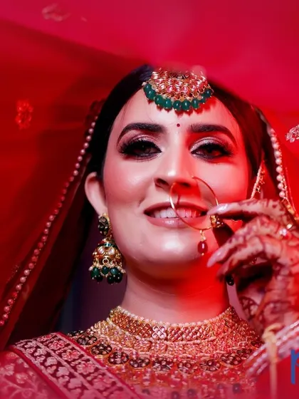 A smiling bridal portrait with a soft, red-toned light, capturing the bride's happiness and the beauty of her veil.