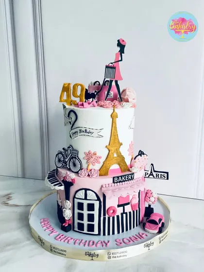 A Parisian-inspired beauty for a 49th birthday. This cake is a masterpiece featuring the Eiffel Tower, a chic shopping lady, and a Parisian street scene.