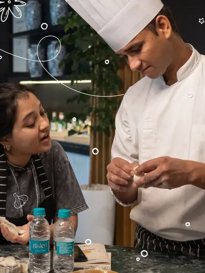 A chef provides one-on-one guidance to a participant, showing her the delicate technique for folding a dumpling. This personal attention helps everyone learn at their own pace.