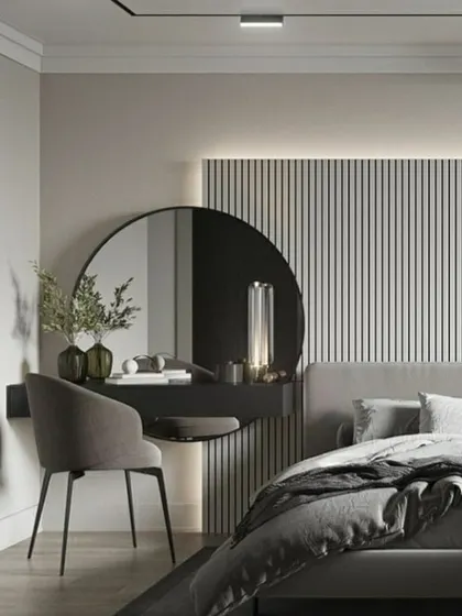 A beautifully minimalist and functional vanity area within a bedroom. The floating dressing table with a large circular mirror is set against a backdrop of vertical wall paneling and soft backlighting. This design creates a chic and tranquil corner that is both practical and elegant.