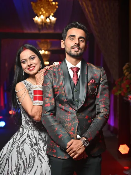 A stylish reception portrait of the couple, showcasing their modern evening attire and the happy smiles they share.