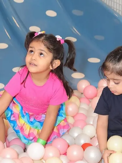 Two young children exploring and playing together in the ball pit.
