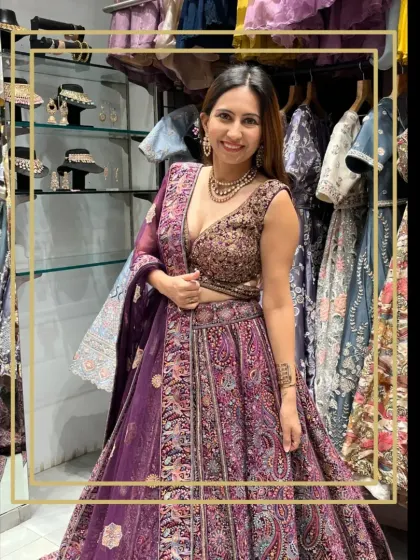 A client trying on a rich purple lehenga with intricate paisley embroidery in my store. The smile on her face says she's found the one.