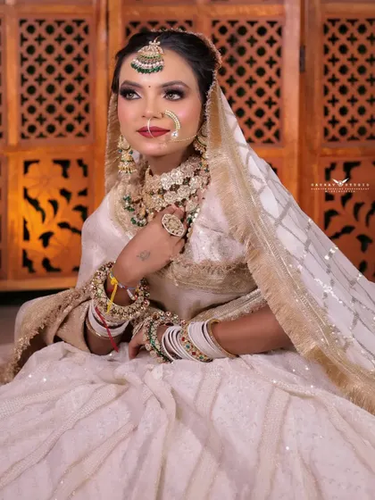 A graceful seated portrait showing the bride looking away. This angle highlights the details of her dupatta and the side profile of her jewellery.