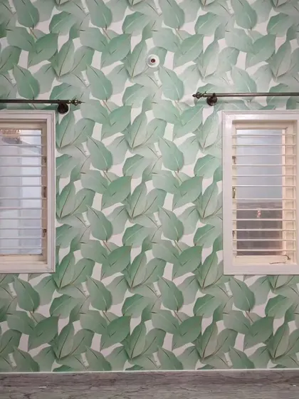 A bedroom with a large green leaf wallpaper, creating a vibrant and refreshing accent wall.