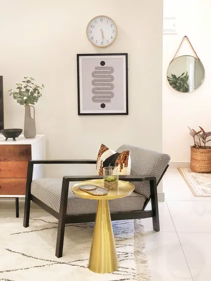 A cozy corner in the JWD Marq Home, perfect for reading and lounging. The modern armchair is paired with a brass side table, creating a simple yet stylish spot to relax.