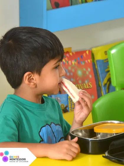 Even snack time is a lesson in independence. This child enjoys his sandwich, having taken responsibility for his own meal.