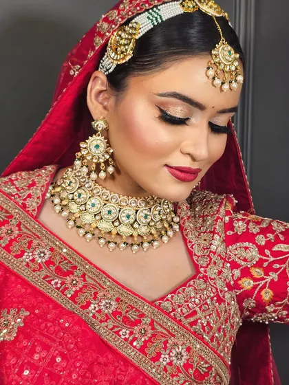 A close-up of a soft glam bridal look with a red outfit. The eyes have a subtle shimmer with a sharp wing, paired with a classic red lip for a timeless appeal.