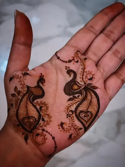A simple yet charming example of my minimalist henna art. This design features two small, elegant peacocks on the palm, connected by a delicate beaded chain, perfect for someone who wants a touch of tradition without full coverage.