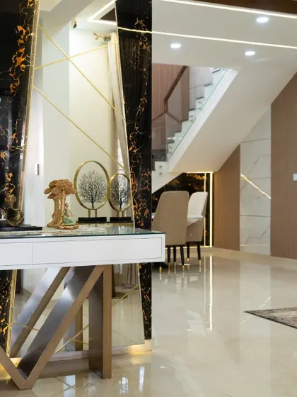 This is how you make a grand entrance. The combination of black marble with gold veins, geometric gold accents, and curated decor pieces on a sleek console table immediately elevates the space to one of pure luxury.