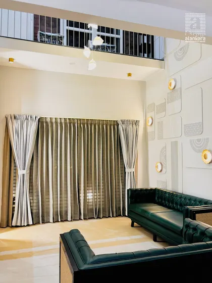 Another view of this grand living space, highlighting the interplay between the custom green sofa, the elegant curtains, and the intricate wall decor. The open mezzanine above adds to the sense of scale.