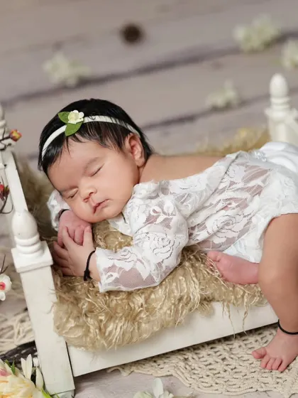 Another angle of the newborn on the tiny bed, showing her delicate lace outfit and peaceful sleep.