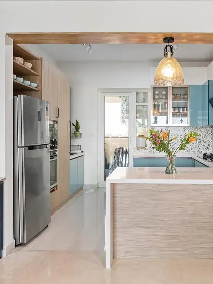 This kitchen design combines two tones of blue with natural wood for the tall unit, creating a layered and interesting color palette. The open layout connects it beautifully to the dining area.