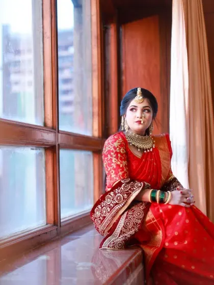 The bride by the window, with natural light highlighting her flawless makeup and the rich color of her saree.