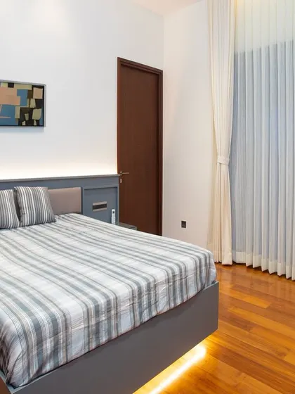 This bedroom demonstrates how simple design can make a big impact. The floating bed with under-lighting creates a sense of lightness, while the warm wood floors add a cozy, natural feel.