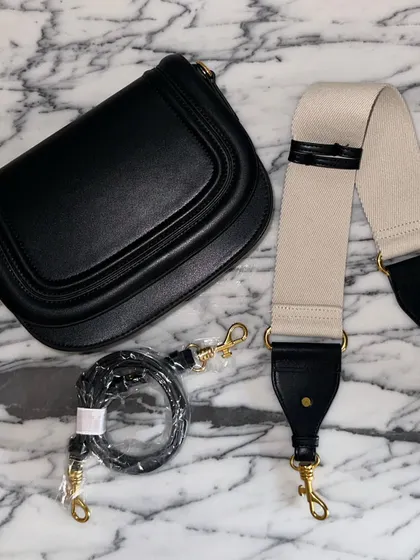 The black Noble bag with its two strap options. The contrast between the black leather and the off-white fabric strap creates a very modern and stylish look.