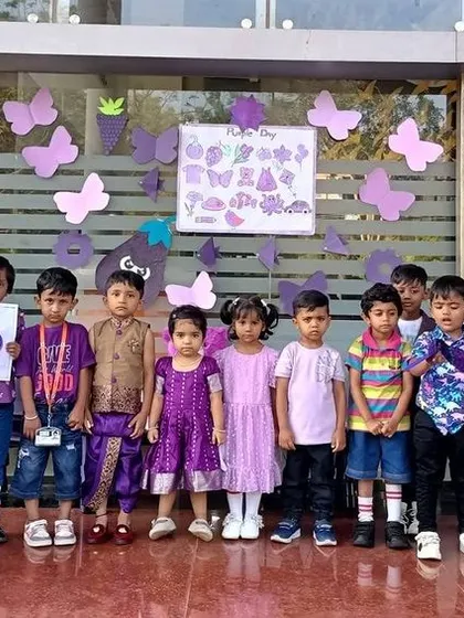 A full class photo of students dressed in purple, holding up purple objects and artwork.