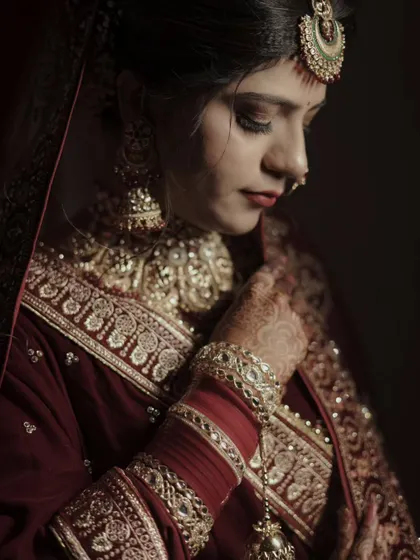 A side profile of the bride in a quiet, thoughtful pose. The lighting beautifully sculpts her features and highlights her jewelry.