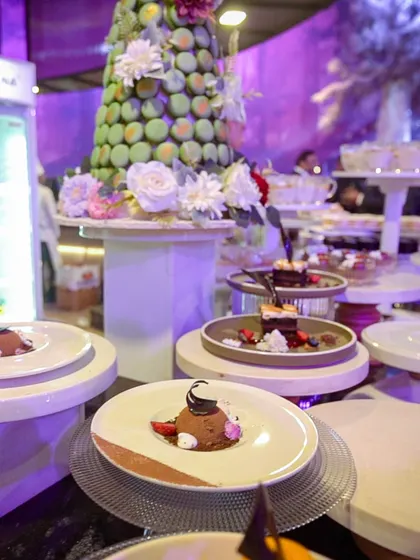 A dessert station at a large event, featuring a pistachio macaron tower and individually plated desserts. Our dessert buffets are designed to be a visual centerpiece.