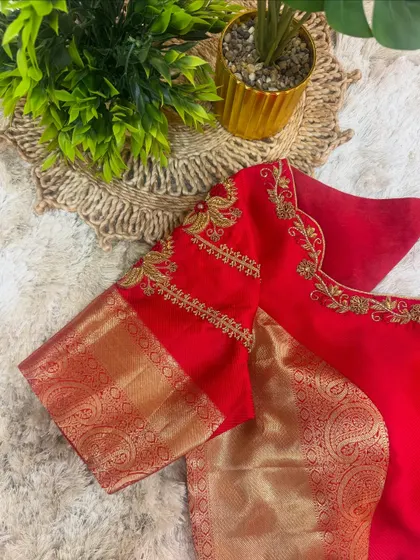 A view of the sleeve of the red blouse, showing the combination of traditional zari fabric and custom floral embroidery.