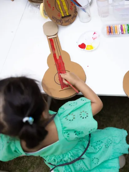 An overhead shot of a little girl painting a cardboard guitar, one of the many hands-on activities we design to make parties more engaging and memorable.