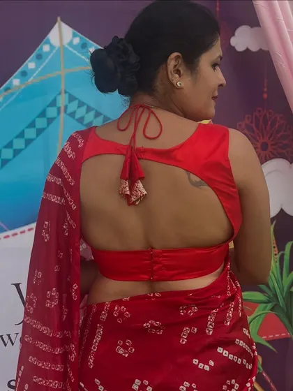 The back of this red bandhani saree blouse features a modern cutout design with a tie-up, combining tradition with a contemporary edge.