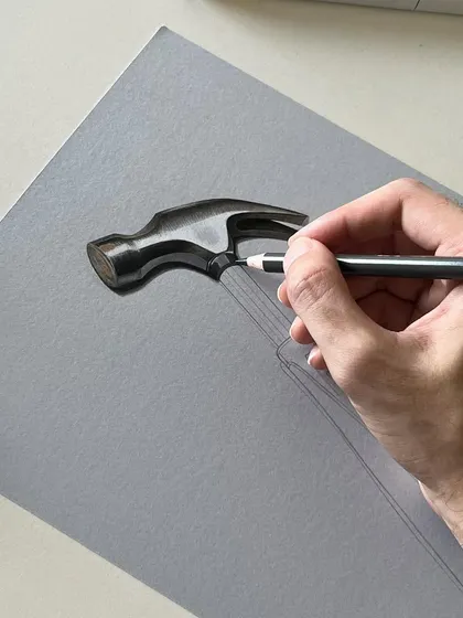 A close-up of the hammer drawing in progress. You can see how I use a black color pencil to define the contours and add depth to the handle before adding the final highlights.