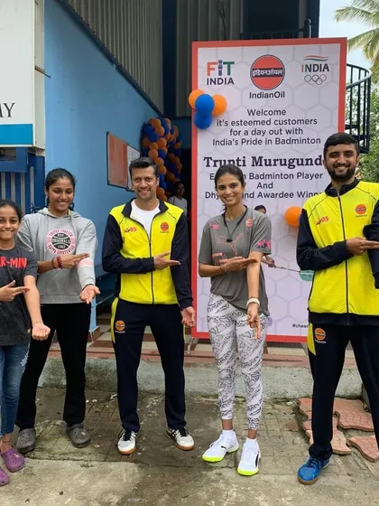 Our students and coaches pointing to the Fit India logo during an event with IndianOil, joined by professional badminton player Trupti Murgunde.