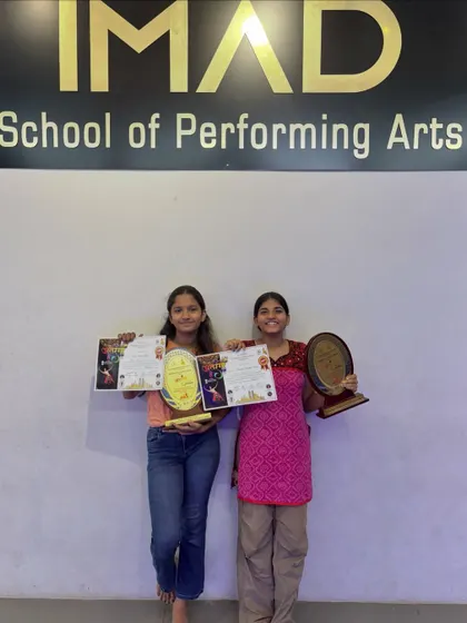 Our two winners posing proudly with their trophies and certificates under the IMAD banner.